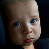 baby, child, face, blue_eyes, close_up, portrait, expression, pout, infant, skin, seatbelt, fabric, clothing, person, young, cute, baby_face, head, looking, indoors