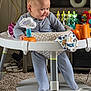 baby, child, smiling, blue_onesie, baby_activity_center, toys, carpet, furniture, indoor, play, face, person, cute, infant, happy, sitting, cloth, patterned, home, floor