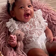 Ellianna joined the competition — help win amazing prizes! baby, infant, smiling, white_lace, headband, flower, basket, pink_fur, knitted_toy, teddy_bear, cute, happy, child, portrait, cozy, soft_texture, indoors, playful, adorable, relaxed