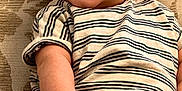 Ovi is registered to the contest to win money with this photo: baby, infant, smiling, striped_onesie, couch, patterned_background, happy, child, portrait, skin, face, hand, foot, sitting, cute, young, indoors, cozy, comfort, expression