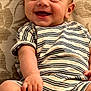baby, infant, smiling, striped_onesie, couch, patterned_background, happy, child, portrait, skin, face, hand, foot, sitting, cute, young, indoors, cozy, comfort, expression