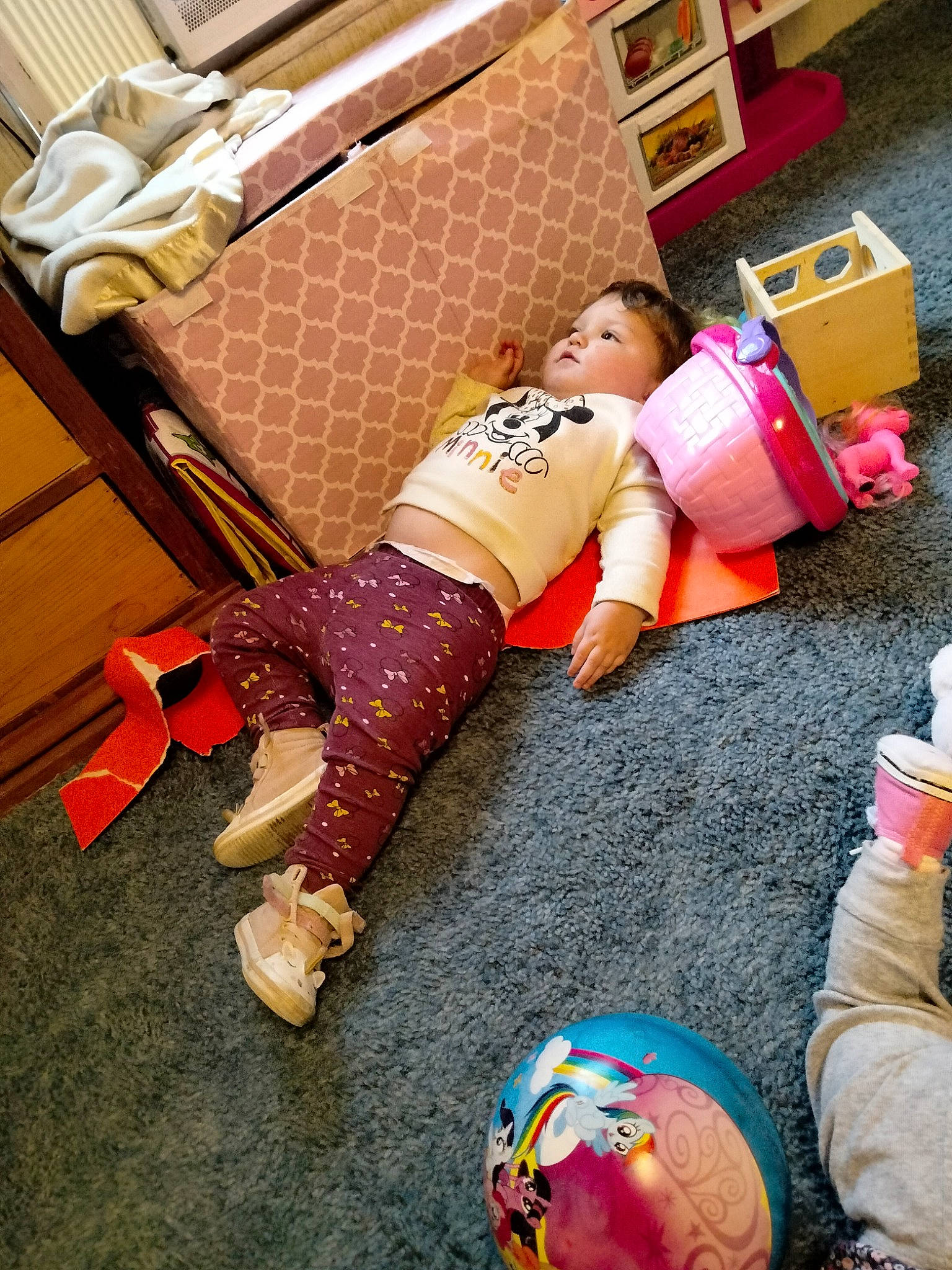 Lilly is registered to the contest to win money with this photo: abdomen, event, floor, flooring, foot, fun, hardwood, human_leg, knee, leisure, orange, person, physical_fitness, room, sitting, sock, sportswear, thigh, toddler, toy