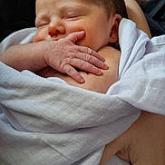 Emma is registered to the contest to win money with this photo: newborn, baby, infant, sleeping, swaddled, blanket, portrait, face, hand, indoors, couch, cozy, peaceful, resting, eyes_closed, white_clothing, head, closeup, home, family