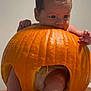 baby, pumpkin, diaper, feet, hands, face, orange, cute, infant, playful, hollow, chewing, messy, skin, toes, leg, indoor, table, holiday, halloween