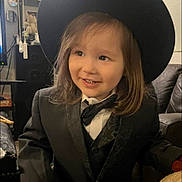 Thomas joined the competition — help win amazing prizes! child, young_child, smiling, portrait, indoor, formalwear, suit, bow_tie, black_hat, long_hair, brown_hair, face, teeth, seated, living_room, couch, home, happy, fashion, photography