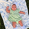 Dailanys is registered to the contest to win money with this photo: baby, infant, blanket, headband, flower, dress, green_dress, socks, white_socks, grass, outdoor, cute, smiling, lying_down, child, person, nature, happy, portrait, baby_girl