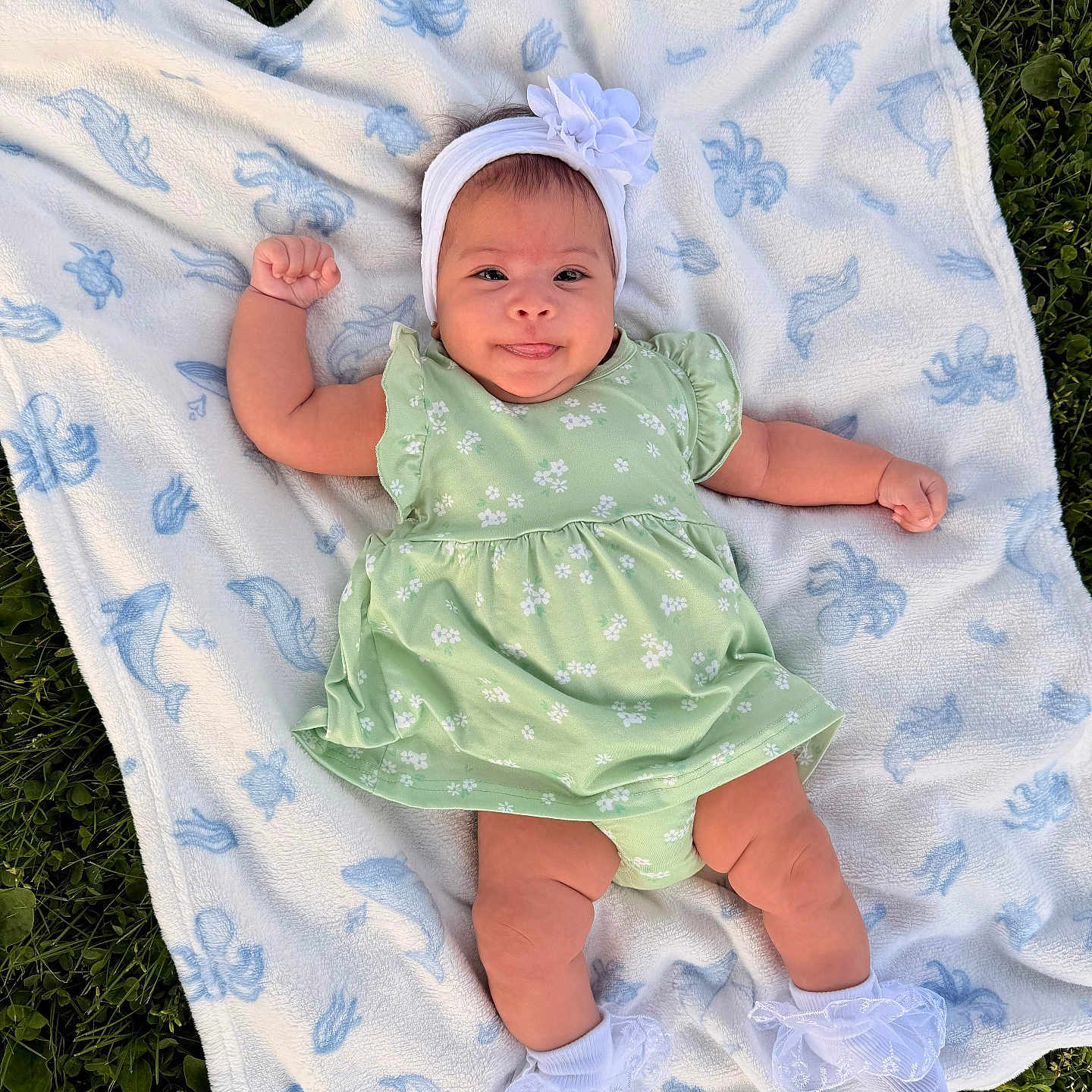 Dailanys is registered to the contest to win money with this photo: baby, infant, blanket, headband, flower, dress, green_dress, socks, white_socks, grass, outdoor, cute, smiling, lying_down, child, person, nature, happy, portrait, baby_girl