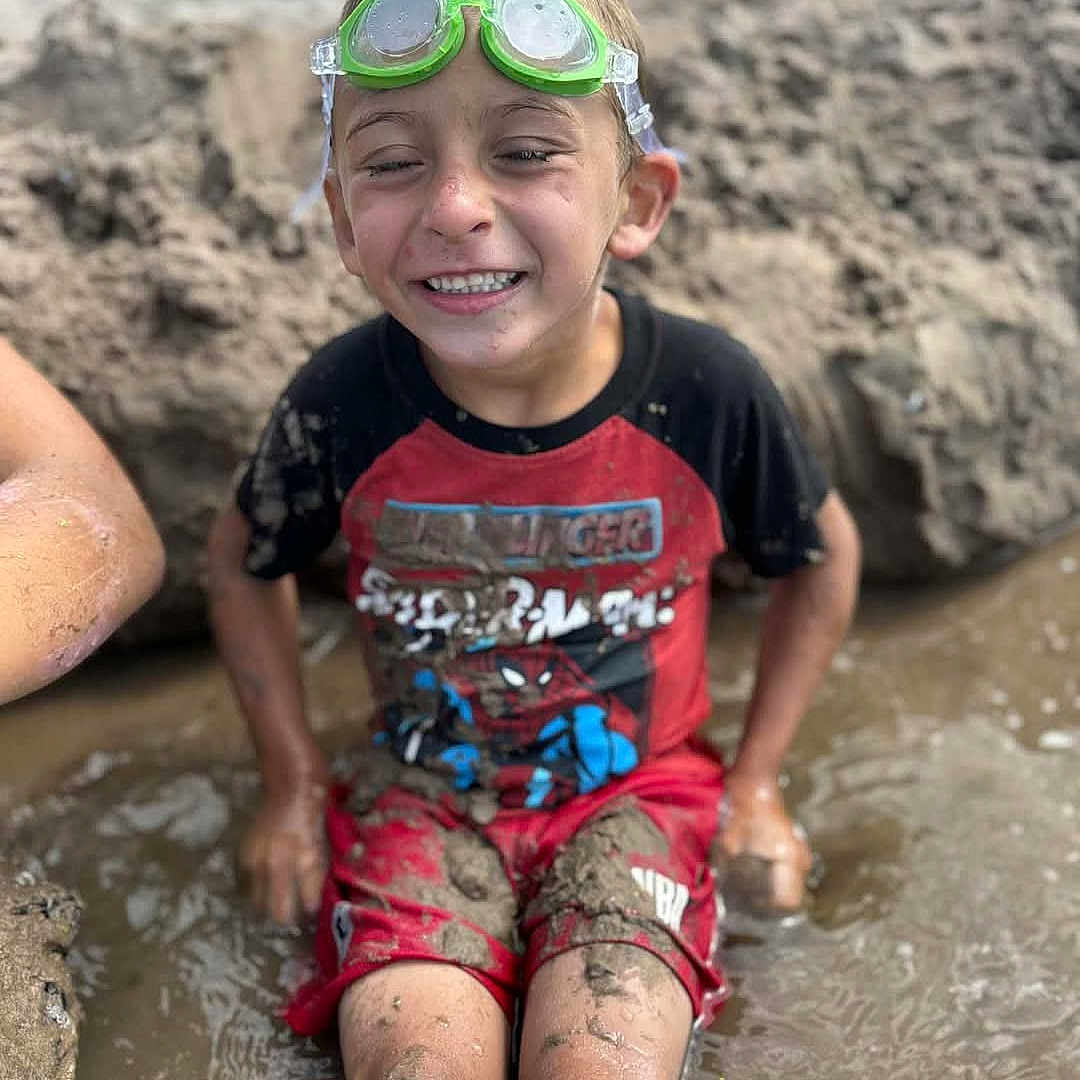 Bentley joined the competition — help win amazing prizes! boy, casual_clothing, child, dirt, fun, goggles, happy, messy, mud, nature, outdoor, play, puddle, red_shorts, sitting, smiling, spiderman_shirt, summer, water, wet