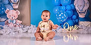 Liam is registered to the contest to win money with this photo: baby, balloons, birthday, blue, celebration, child, cute, decorations, first_birthday, floor, happy, indoor, infant, outfit, party, photo_shoot, sign, sitting, smiling, teddy_bear