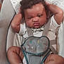 baby, child, curly_hair, baby_carrier, white_shirt, socks, indoor, seat, straps, expression, hands_behind_head, cute, infant, face, legs, footwear, furniture, person, plush, funny_face
