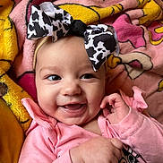 Vivian joined the competition — help win amazing prizes! baby, smiling, bow, headband, pink_clothing, blanket, cartoon_pattern, face, infant, happy, child, cute, indoors, cozy, closeup, portrait, hand, fingers, apparel, soft_toy