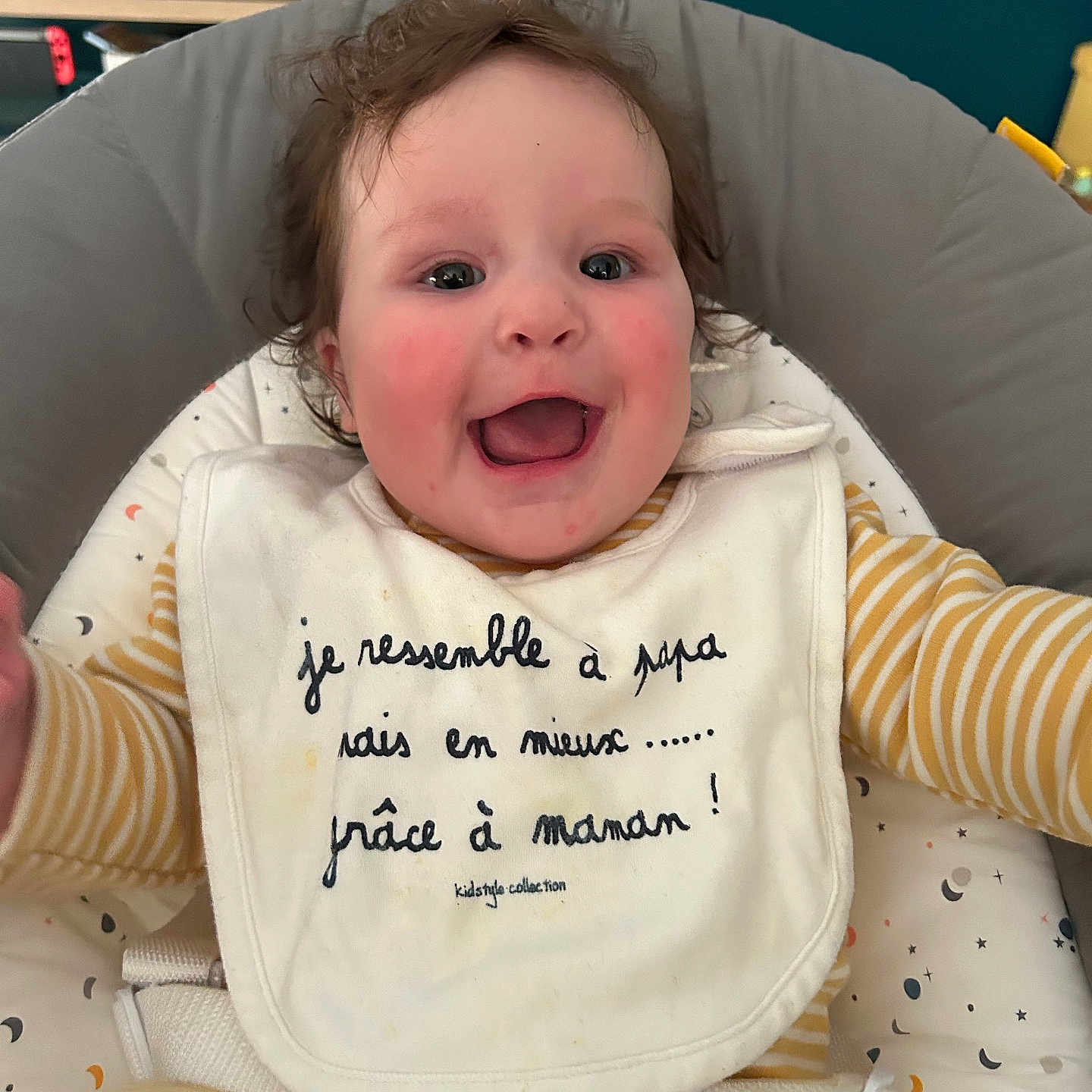 Jade participe au concours pour gagner de l'argent avec cette photo : baby, bib, cheeks, child, closeup, comfortable, curly_hair, cushion, cute, expression, face, happy, indoor, infant, joy, person, playful, seat, smiling, striped_clothing