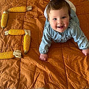 Jade a rejoint le concours — aidez-le/la à gagner de superbes lots ! baby, child, crawling, blue_clothing, corn, corn_cobs, letter_e, blanket, brown_blanket, happy, smiling, indoors, cute, face, head, hands, polka_dot, patterned_clothing, playful, infant