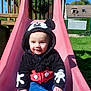 baby, child, slide, playground, hoodie, mickey_mouse, outdoor, smiling, sunny, grass, blue_sky, house, fence, clothing, person, cute, sitting, fun, daytime, park