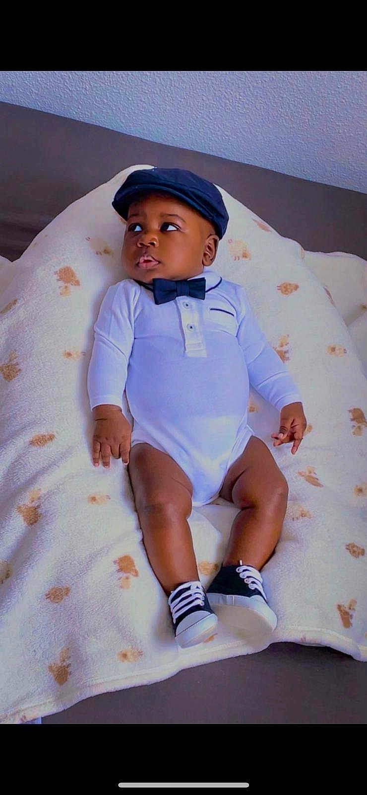 Momo participe au concours pour gagner de l'argent avec cette photo : baby, blanket, bow_tie, boy, cap, child, clothing, couch, cute, expression, fashion, footwear, indoor, infant, onesie, portrait, relaxing, shoes, sitting, young_child