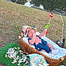 Angel is registered to the contest to win money with this photo: baby, infant, child, outdoor, lakeside, pond, basket, bassinet, fishing, fishing_rod, fishing_float, sun_hat, knitwear, blue_clothing, sleeping, smiling, shells, decorative_fish, grass, nature