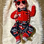 baby, infant, heart_shaped_sunglasses, sunglasses, bow_tie, bandana, suspenders, red_outfit, valentines_theme, fur_rug, blanket, lying_down, portrait, cute, accessory, red_socks, patterned_pants, carpet, hat, hand