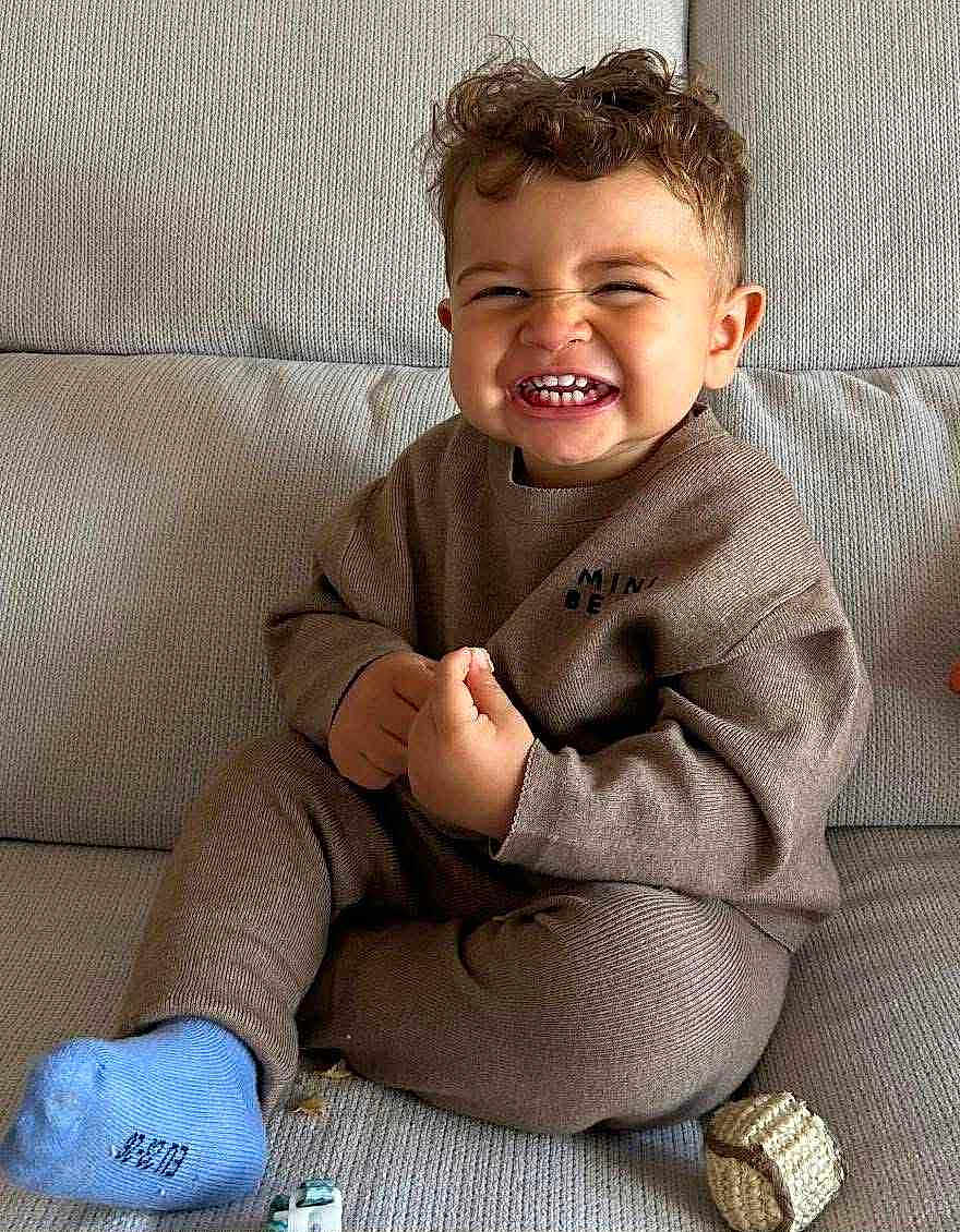 Méziane a rejoint le concours — aidez-le/la à gagner de superbes lots ! toddler, child, smiling, curly_hair, brown_outfit, blue_socks, couch, indoor, happy, toys, playful, cute, portrait, sitting, baby, cozy, expression, hands, face, clothing