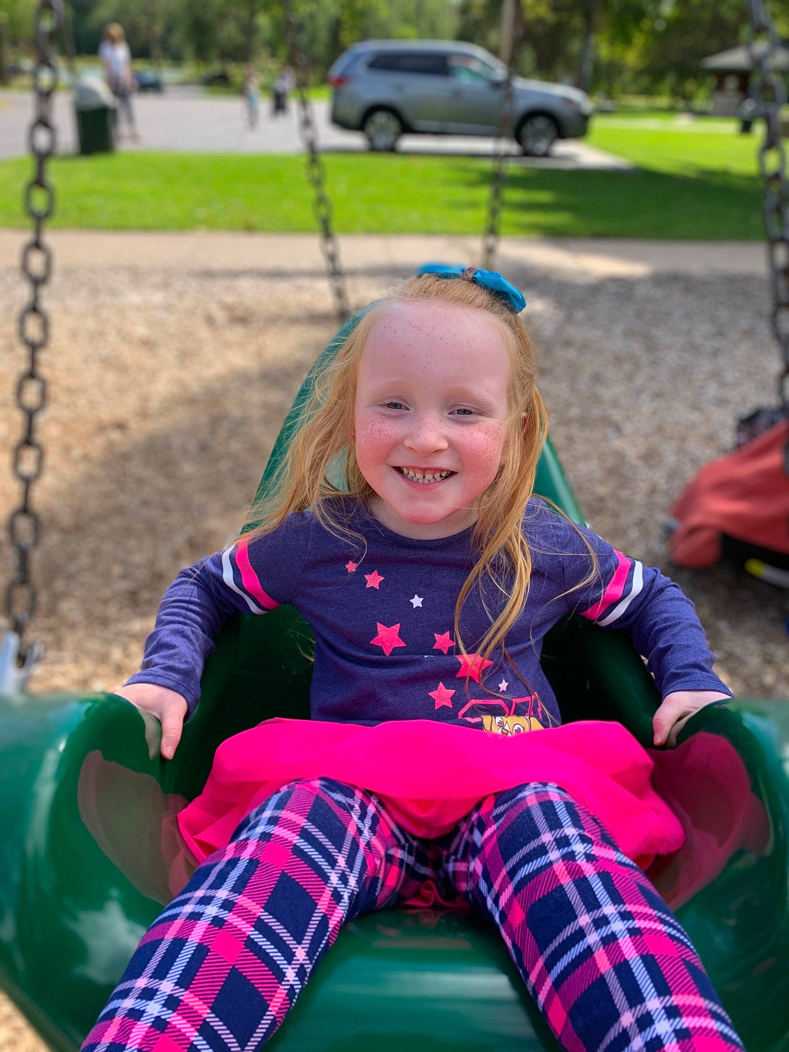 Izabel joined the competition — help win amazing prizes! child, design, fun, grass, joy, leisure, outdoor_play_equipment, pattern, person, pink, plaid, plant, play, playground, public_space, recreation, sitting, smile, swing, tartan