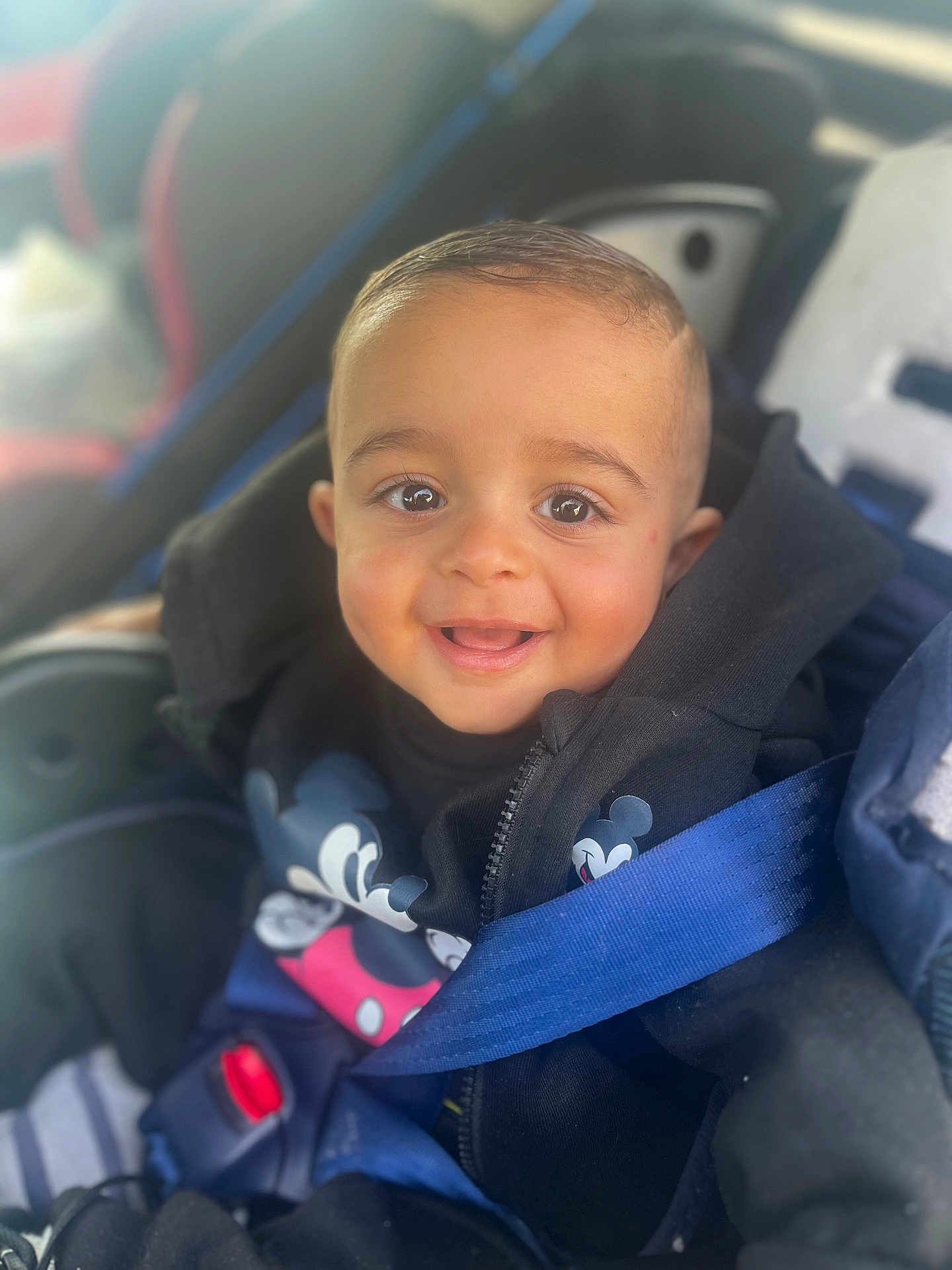 Khemys a rejoint le concours — aidez-le/la à gagner de superbes lots ! baby, child, car_seat, seatbelt, black_jacket, mickey_mouse, smiling, happy, face, person, young_child, clothing, safety, car_interior, cute, portrait, infant, hoodie, closeup, bright_eyes