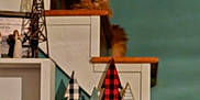 Winston Chole is registered to the contest to win money with this photo: cat, stairs, orange_cat, wooden_railing, holiday_decorations, plaid_trees, figurines, shelf, framed_photos, home_interior, decor, wood, teal_wall, cozy, indoor, pet, feline, relaxed, animal, domestic