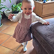 Kalya a rejoint le concours — aidez-le/la à gagner de superbes lots ! child, toddler, baby, smiling, dress, socks, standing, living_room, plants, potted_plant, toys, wooden_drawer, couch, floor_tiles, happy, cute, hand, face, eyes, portrait