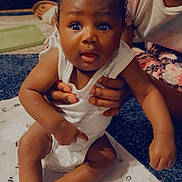 Khyzun Cooper is registered to the contest to win money with this photo: baby, child, infant, person, hands, blanket, curly_hair, indoor, carpet, white_clothing, cute, expression, skin, face, foot, toe, sitting, holding, pattern, floor