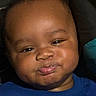 Legend joined the competition — help win amazing prizes! baby, face, close_up, child, expression, pout, blue_shirt, cute, infant, portrait, young_child, skin, head, person, smile, indoors, dark_background, tongue, happy, chubby_cheeks