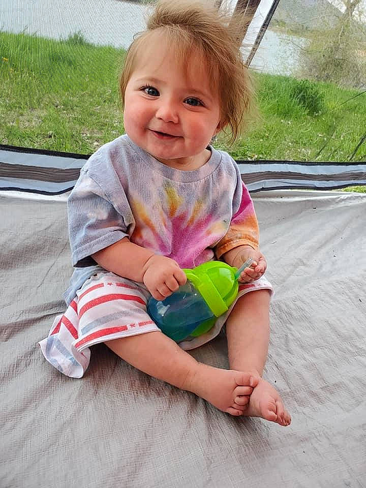 Lilith is registered to the contest to win money with this photo: baby, baby_toddler_clothing, cheek, child, eye, face, facial_expression, fun, grass, hairstyle, happy, head, joy, knee, leisure, person, pink, skin, sleeve, smile