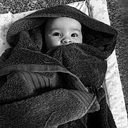 Jaylan is registered to the contest to win money with this photo: baby, child, face, hooded_towel, wrapped, blanket, cozy, soft, star_pattern, mat, indoors, cute, expression, wide_eyes, infant, towel, comfort, rest, portrait, black_and_white