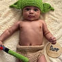 baby, infant, hat, crochet, green_hat, lightsaber_toy, handmade, blanket, lying_down, wooden_sign, two_months, cute, child, face, headwear, soft_texture, portrait, baby_clothing, newborn, indoor