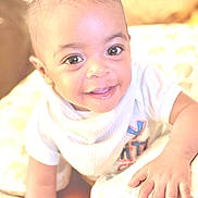 Markel is registered to the contest to win money with this photo: baby, child, smiling, cute, hand, cushion, elephant_print, white_clothing, indoor, closeup, happy, person, infant, face, young_child, soft_lighting, portrait, baby_girl, baby_boy, toddler