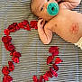 Lee joined the competition — help win amazing prizes! baby, closeup, cute, diaper, face, head, heart_shape, infant, love, lying_down, newborn, pacifier, pattern, red, relaxing, rose_petals, skin, small_hand, soft, striped_blanket