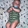 Wyatt is registered to the contest to win money with this photo: baby, infant, pacifier, striped_clothing, plush_toy, stuffed_animal, bed_sheet, marine_animals_pattern, shark, octopus, seahorse, jellyfish, whale, lying_down, child, cute, sleepwear, indoor, soft_toy, person