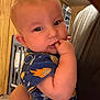 Wyatt is registered to the contest to win money with this photo: baby, infant, child, person, face, hand, fingers, clothing, space_theme, room, wood_paneling, crib, adult, holding, portrait, indoor, cute, curious, sitting, closeup