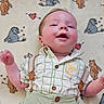 baby, infant, smiling, lying_down, shirt, suspenders, blanket, cartoon_animals, hearts, cute, happy, child, portrait, indoor, soft_texture, cozy, clothing, young_child, face, playful