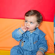 Ange a rejoint le concours — aidez-le/la à gagner de superbes lots ! baby, child, clothing, colorful_background, cute, denim, face, footwear, head, indoor, jumpsuit, orange, person, portrait, red, sitting, thumb_sucking, toddler, yellow, young_child