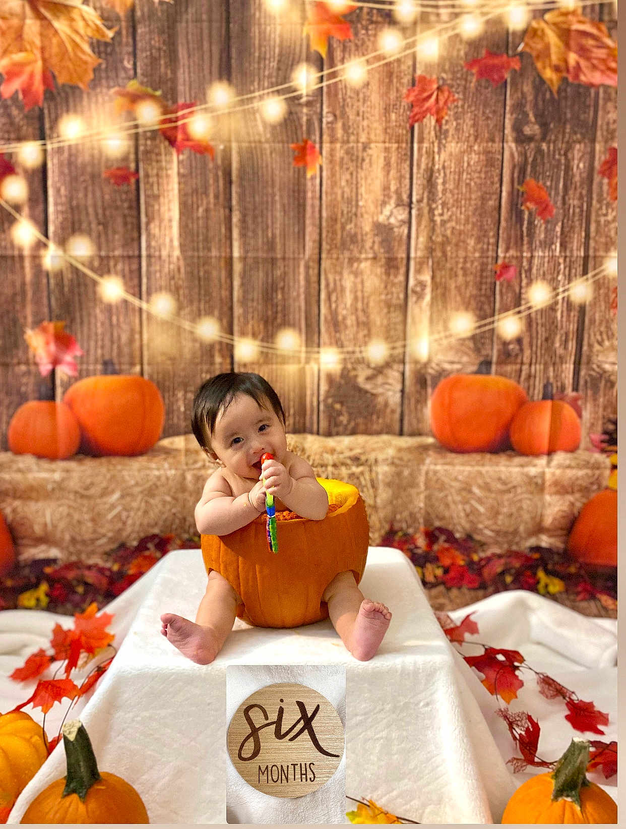 Castiel is registered to the contest to win money with this photo: autumn, baby, child, cute, decorations, fall_leaves, festive, holiday, indoors, infant, orange, portrait, pumpkin, seasonal, sitting, six_months, smiling, string_lights, toy, wooden_backdrop