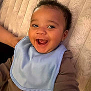 Karsyn joined the competition — help win amazing prizes! baby, smiling, bib, brown_clothing, lying_down, happy, infant, face, cute, child, plush_blanket, closeup, portrait, indoors, soft_texture, joyful, young_child, skin, head, expression