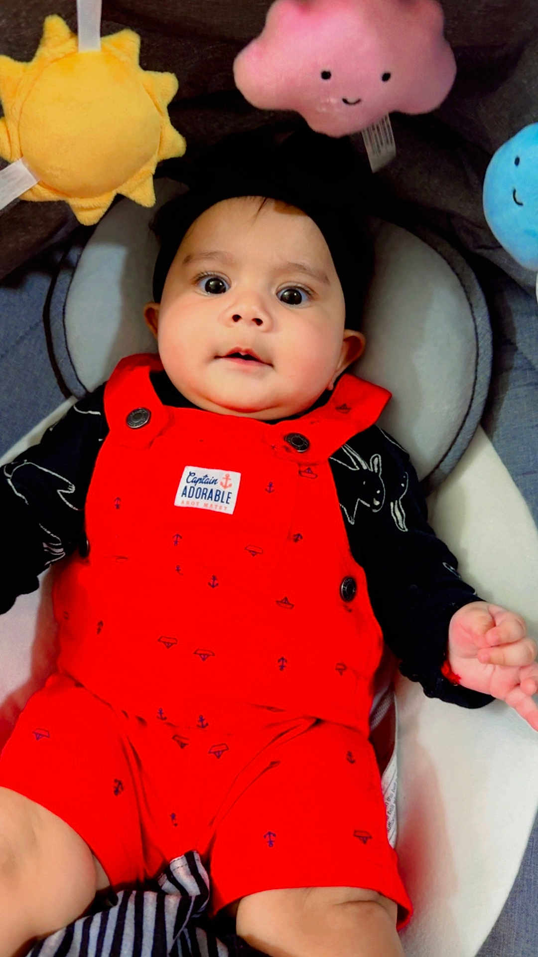 Jinie is registered to the contest to win money with this photo: baby, infant, red_outfit, plush_toy, sun_toy, cloud_toy, raindrop_toy, black_headband, cute, smiling, indoors, child, seat, clothing, person, portrait, happy, soft_toys, closeup, expression