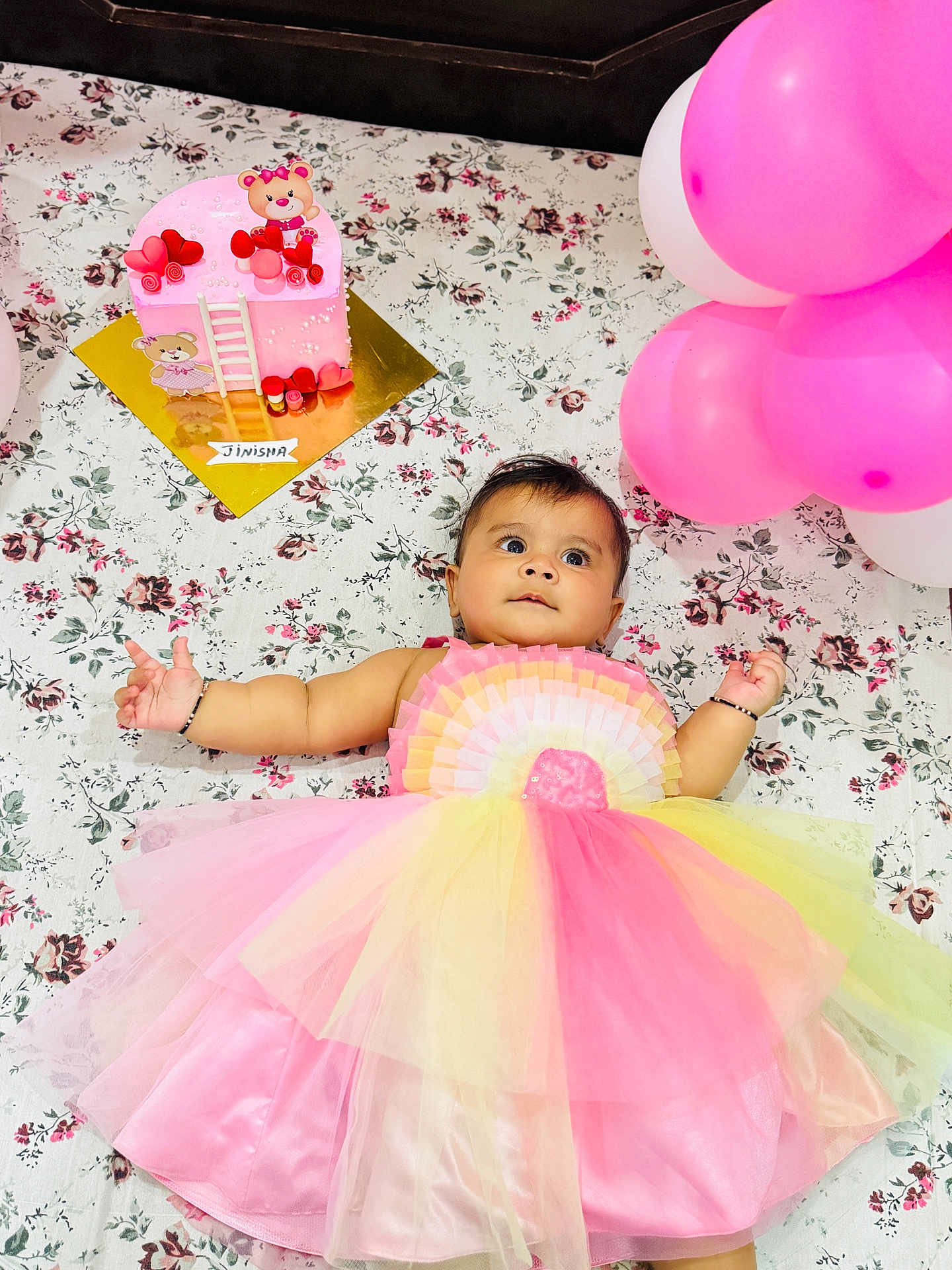 Jinie is registered to the contest to win money with this photo: baby, balloons, birthday, cake, celebration, child, colorful, cute, decorations, dress, festive, floral_blanket, happy, infant, lying_down, party, pink, portrait, toy_bear, yellow