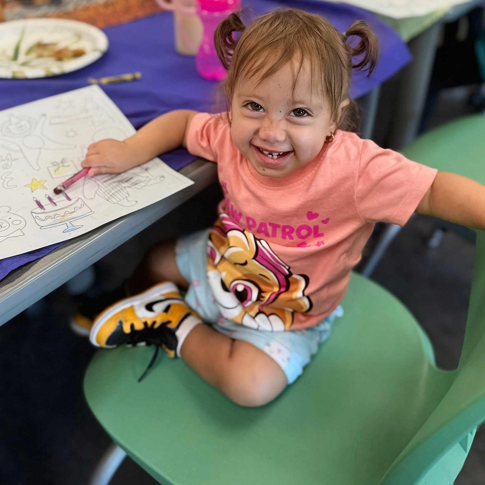 Sarefina joined the competition — help win amazing prizes! child, toddler, smiling, pigtails, pink_shirt, coloring, crayon, paper, chair, green_chair, table, shoes, sneakers, indoor, classroom, happy, person, cute, drawing, playful