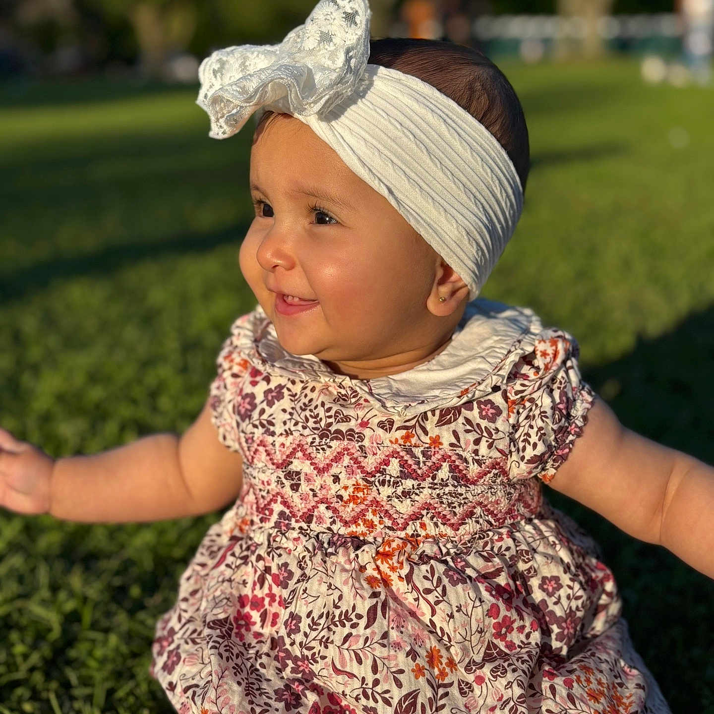 Rima joined the competition — help win amazing prizes! baby, bow, child, cute, face, floral_dress, girl, grass, happy, head, headband, nature, outdoor, park, person, portrait, sitting, smiling, sunlight, young_child