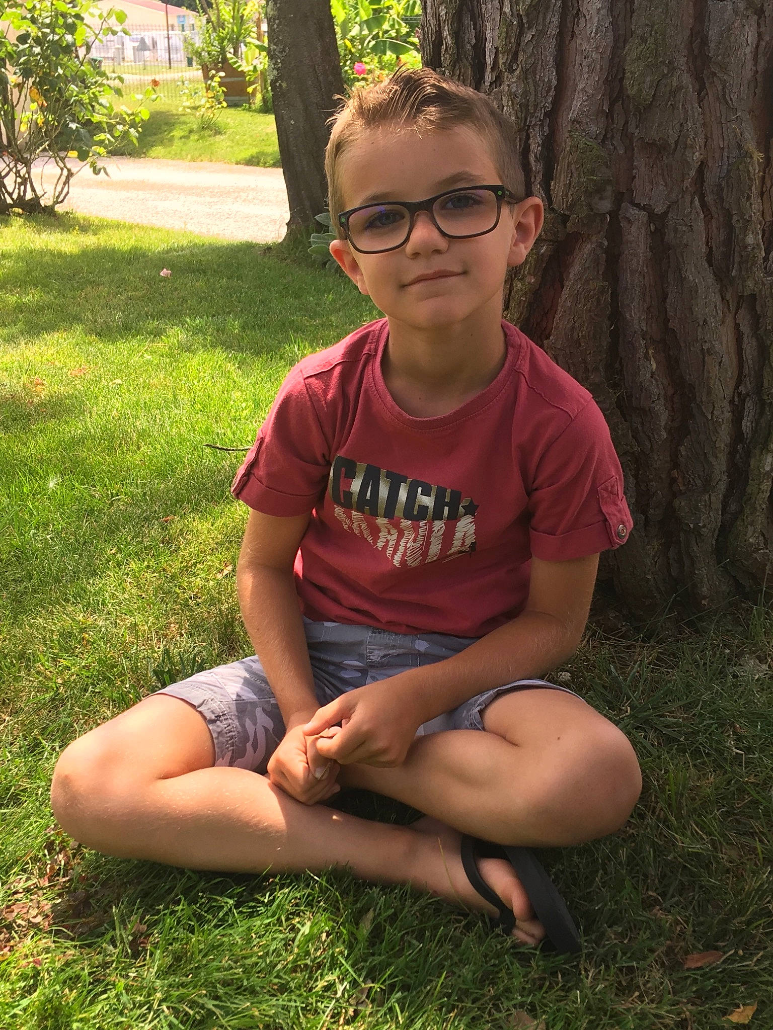 Loïc participe au concours pour gagner de l'argent avec cette photo : arm, child, cool, emotion, facial_expression, fun, girl, glasses, grass, lawn, leg, person, plant, sitting, smile, summer, sunglasses, tree, trunk, vacation