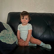 Alonzo joined the competition — help win amazing prizes! toddler, child, baby, couch, leather, pillow, socks, onesie, indoor, furniture, face, person, seated, hair, expression, curious, skin, hand, foot, living_room