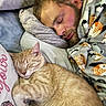 animal, bed, blanket, blanket_pattern, cat, closed_eyes, comfort, cozy, facial_hair, fur, ginger_cat, human, indoor, man, nap, pet, pillow, relaxation, rest, sleeping