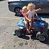 Merrick joined the competition — help win amazing prizes! asphalt, barefoot, car, child, container, curly_hair, handlebar, outdoor, parking_lot, plastic_toy, play, reflection, shadow, shorts, sunlight, toy_atv, toy_sword, tshirt, vehicle, wheel