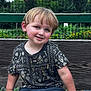 child, boy, smiling, sitting, bench, outdoor, garden, flowers, greenery, fence, casual_clothing, short_hair, daylight, portrait, happy, nature, wood, playful, park, cute