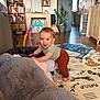 toddler, child, smile, indoor, plush_toy, playmat, toy, furniture, living_room, wooden_shelf, plant, floor, clothing, baby, happy, crawling, home, colorful, person, cute