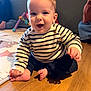 Hélio participe au concours pour gagner de l'argent avec cette photo : baby, child, smiling, striped_sweater, sitting, barefoot, wooden_floor, play_mat, toy, indoor, person, happy, cute, young_child, couch, home, family, casual_clothing, infant, portrait